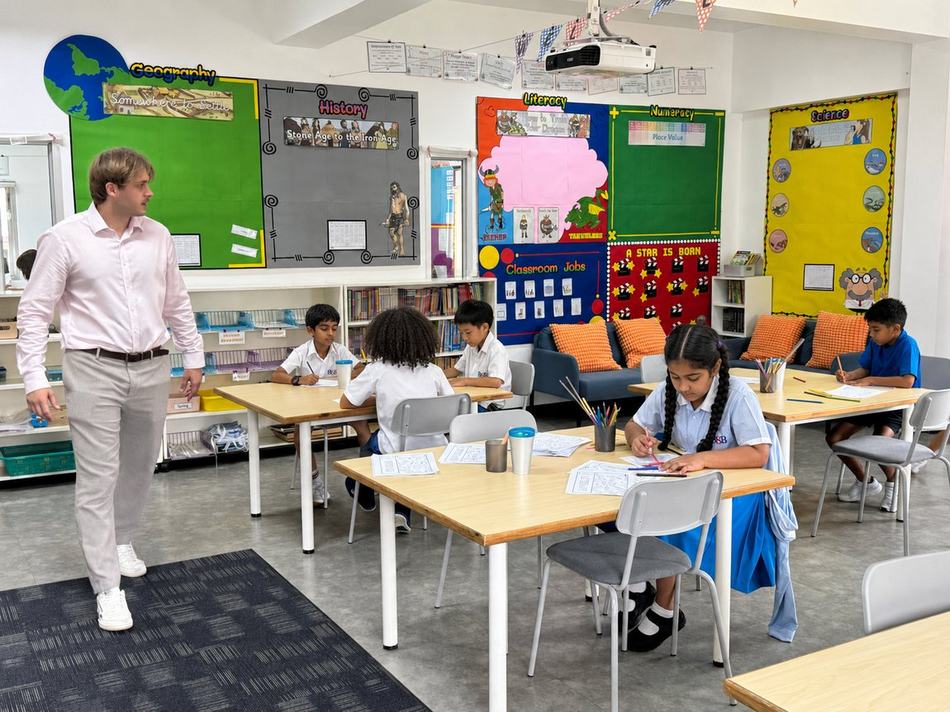 A teacher reviewing a student's work in front of subject display boards