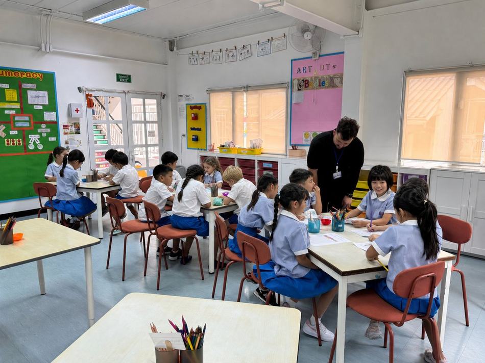 Students working at their desks in front of Art, DT and Numeracy display boards