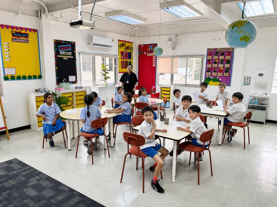 Students working together at their desks in front of the History display board