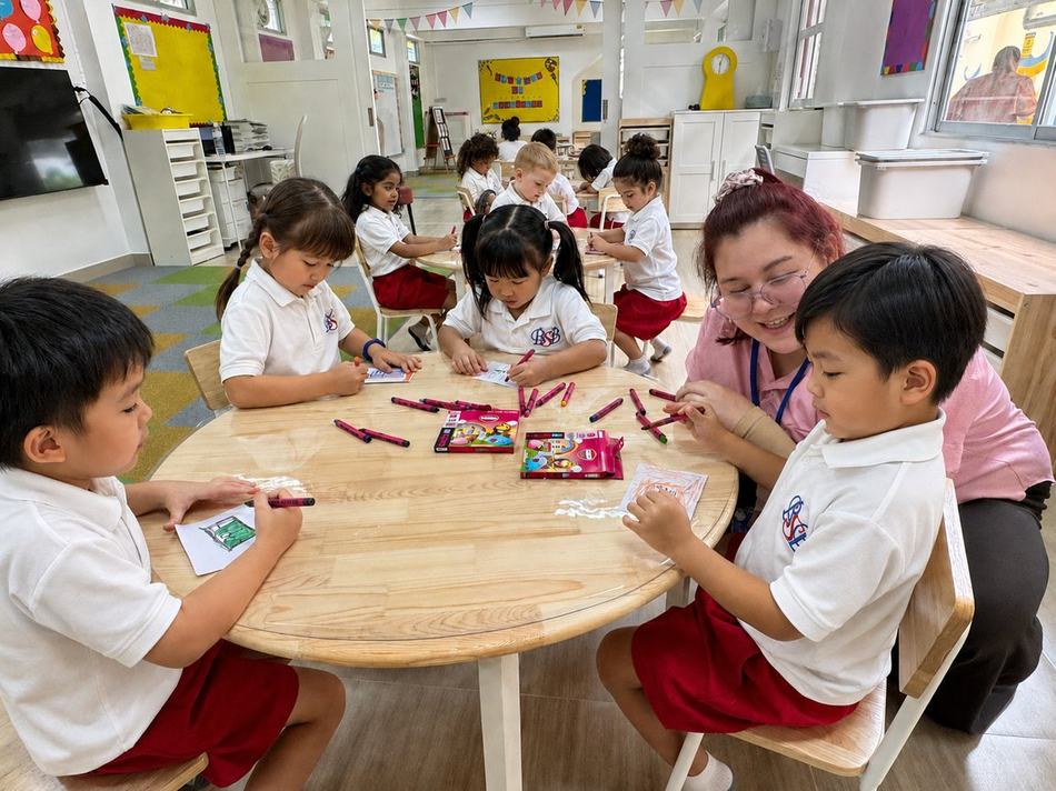 A teacher helping students with a colouring activity at their table