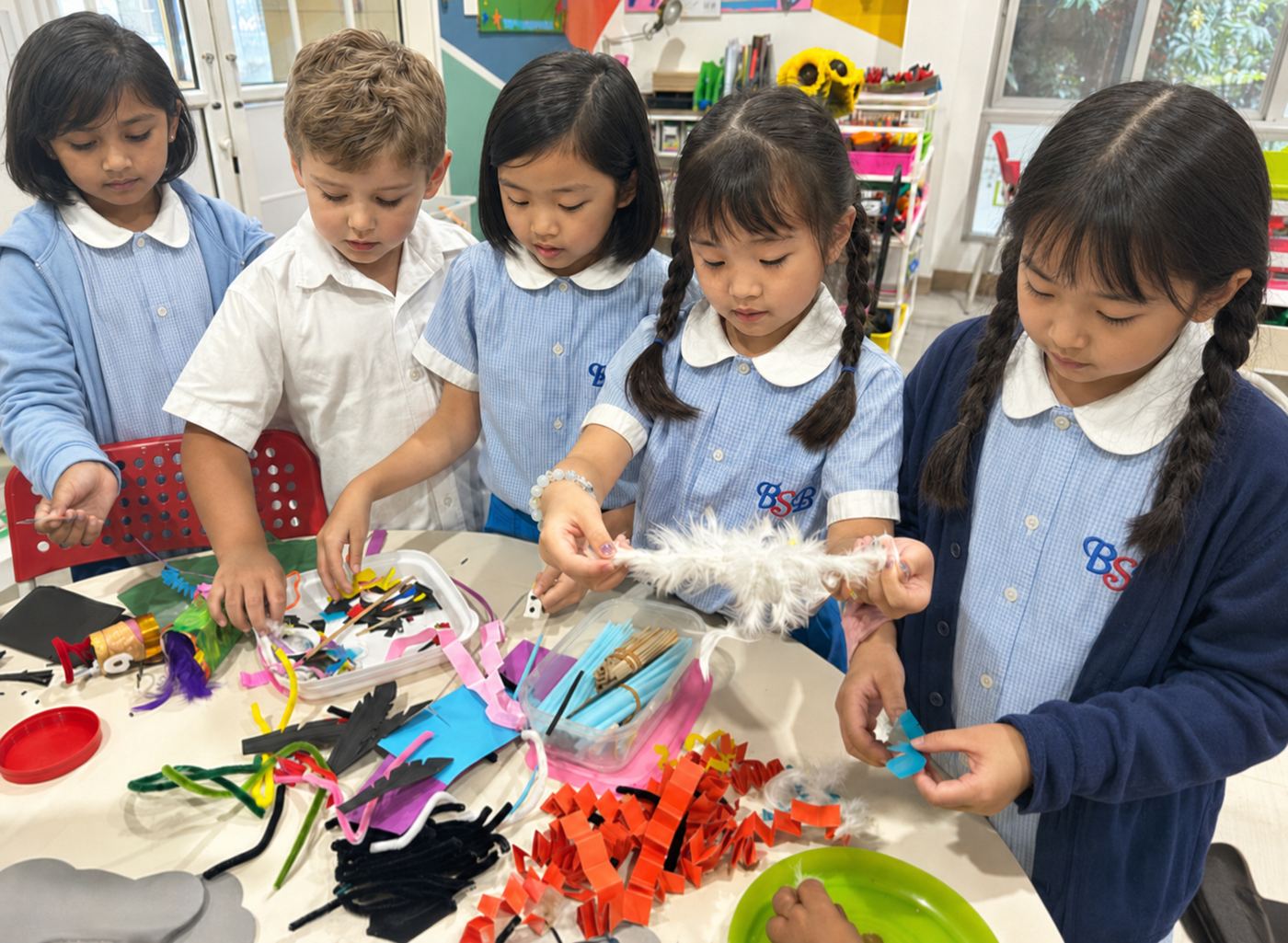 Students making crafts together with feathers and ribbons