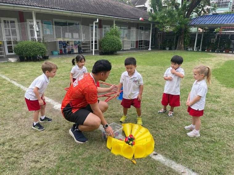 A coach guiding students through a ball game during Ball Skills