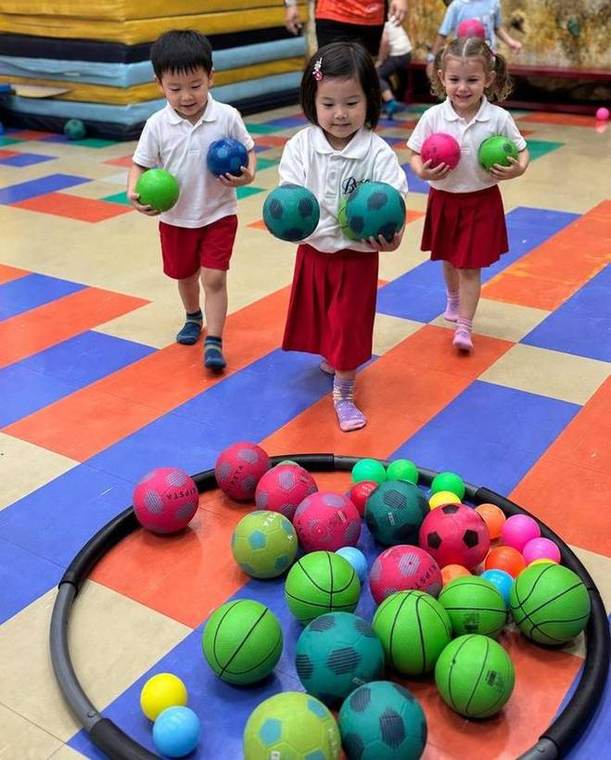 Students carrying balls together during a Junior Gym activity