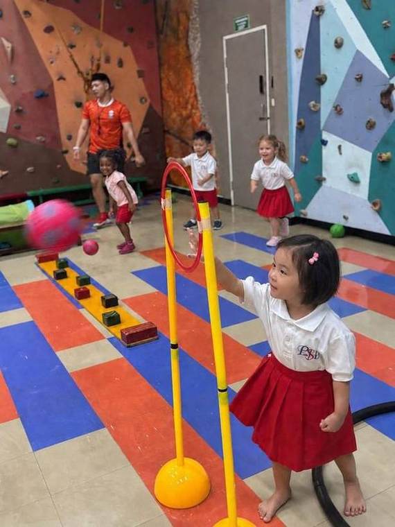 A student reaching for a hoop during a Junior Gym obstacle course