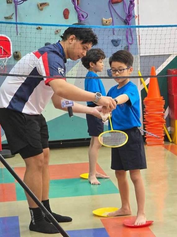 A coach helping a student with their badminton grip during Racket Skills