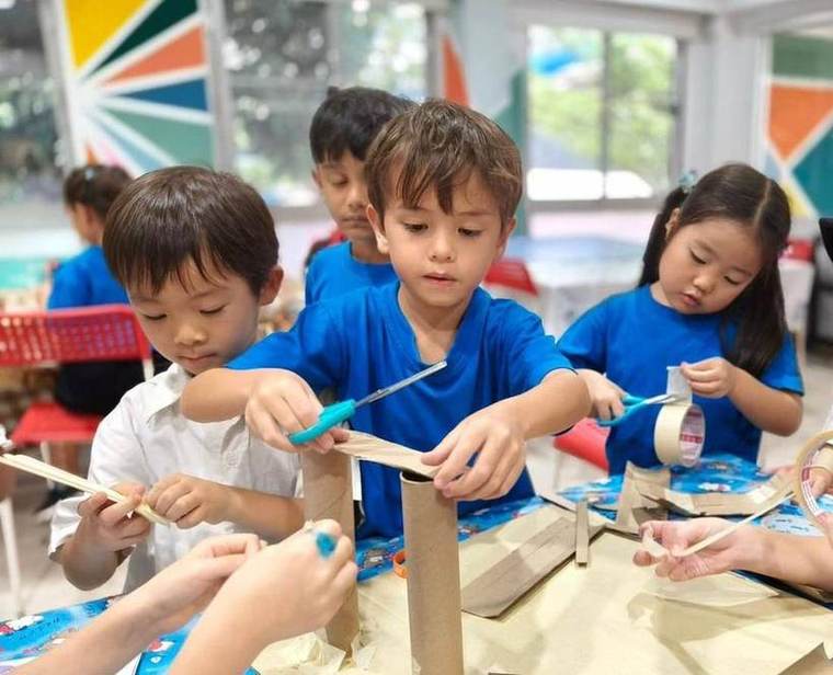 Students building a construction with cardboard tubes and tape during Science Club