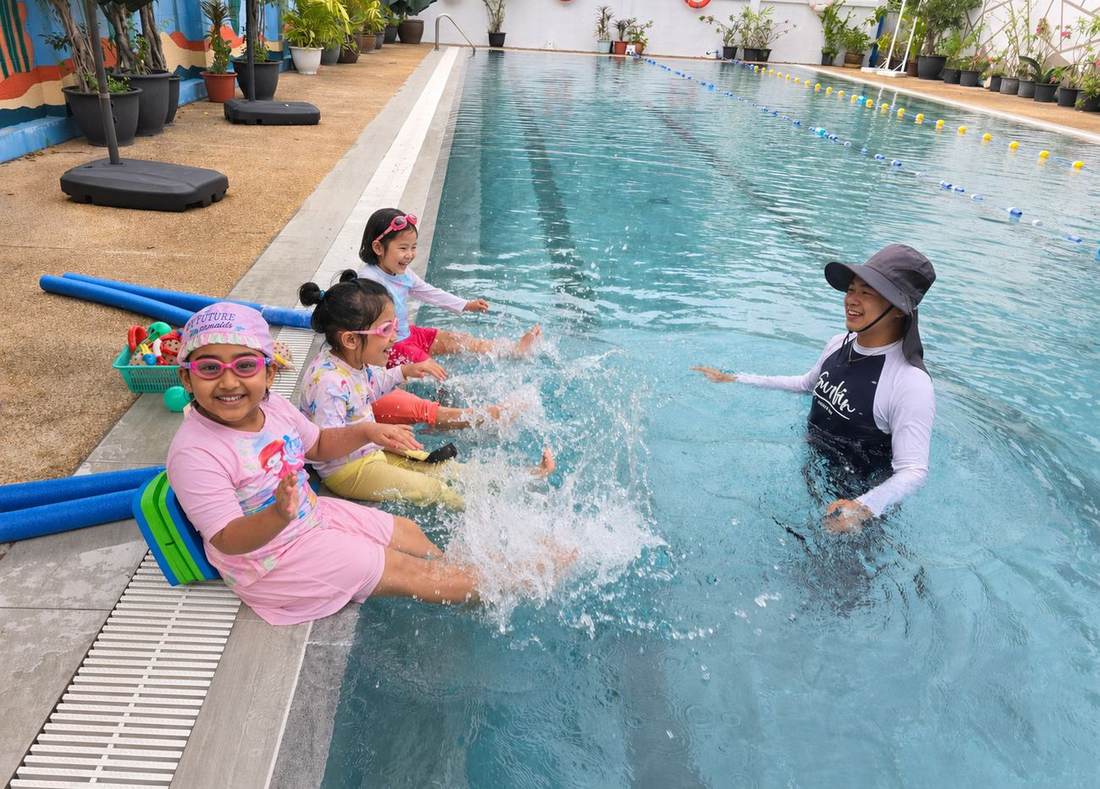 Students smiling at the pool edge during Swimming Club