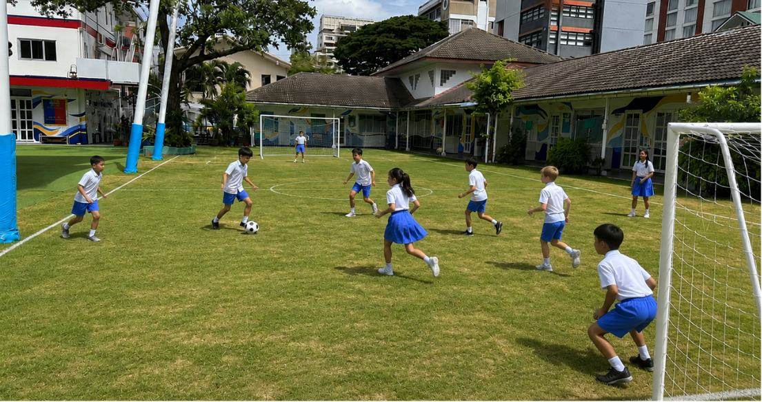 Wide view of students playing football on the school field