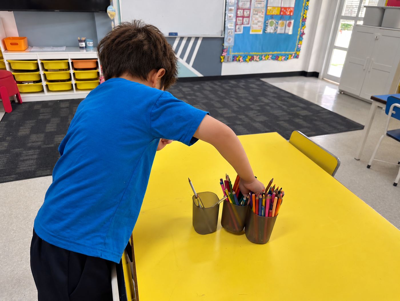 A student tidying pencil pots as part of their classroom role