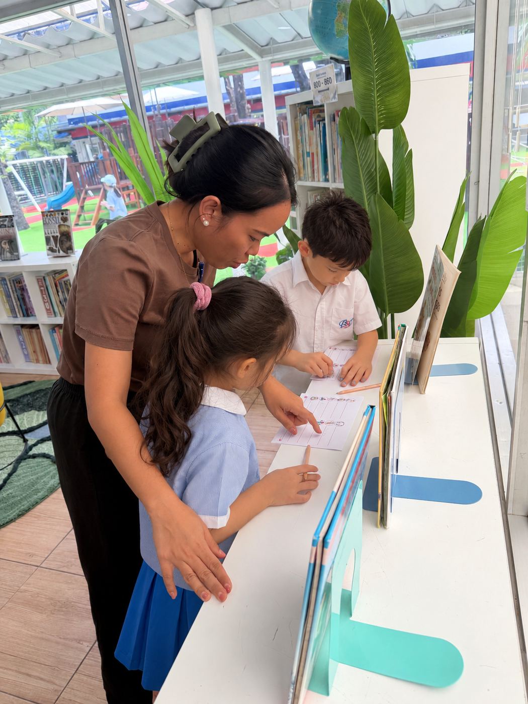 A teacher helping two students with an English language worksheet