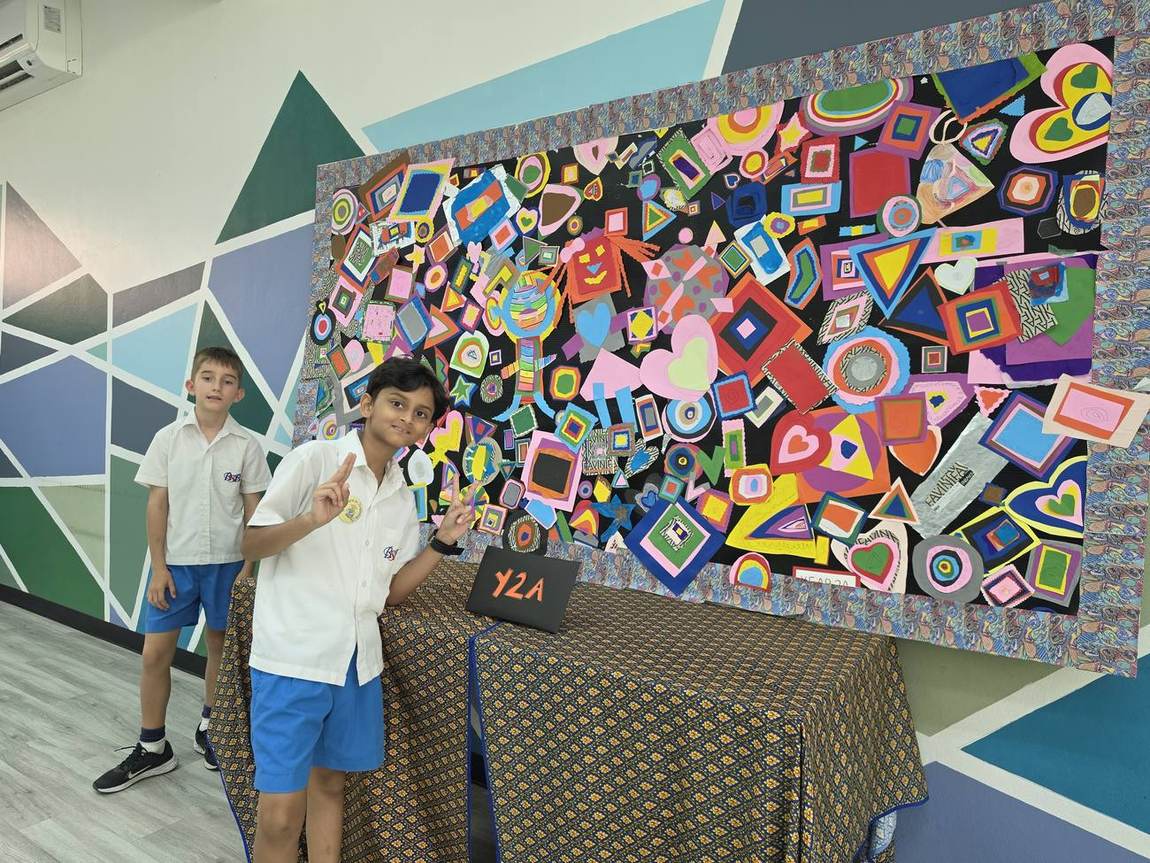 Students posing proudly beside their artwork at the Art Gala