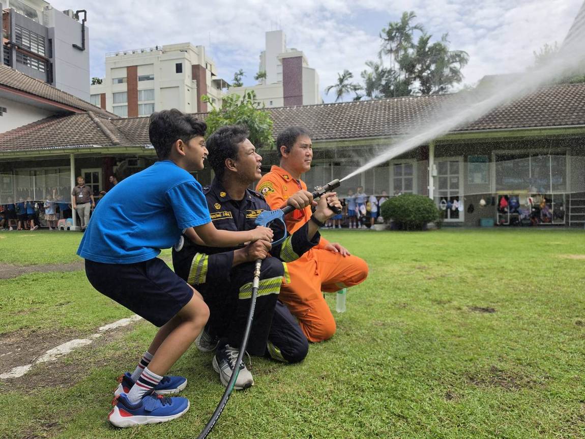 A firefighter helping a student try on protective gear