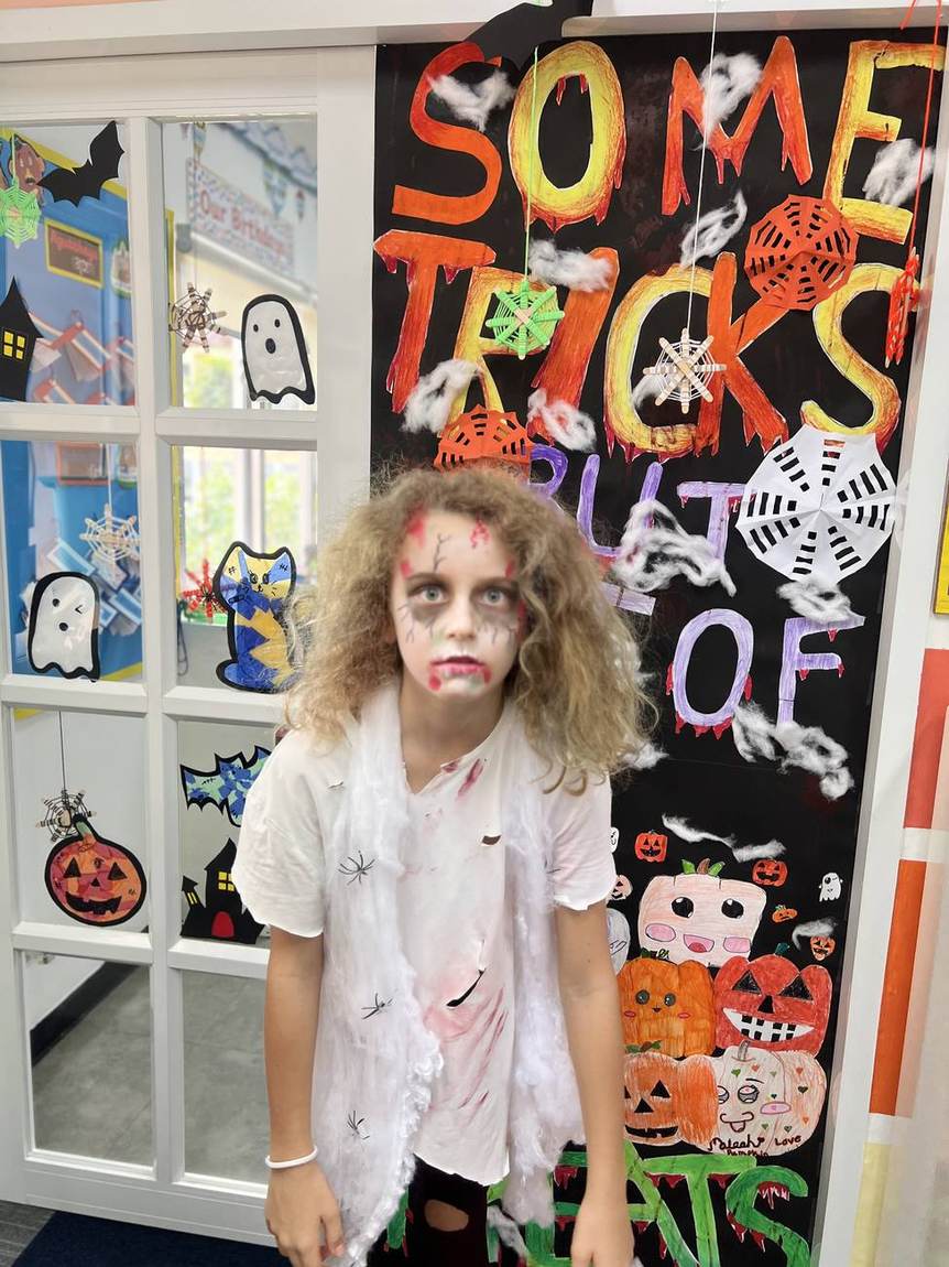 Students in costume under the Happy Halloween banner