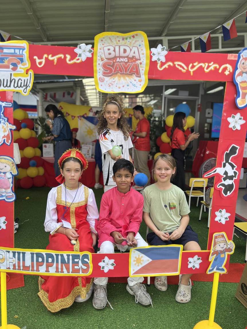 A student greeting a parent volunteer at an International Day food stall