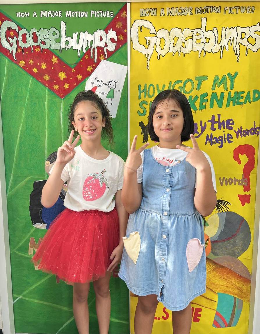 Two students dressed as book characters in front of a classroom door display