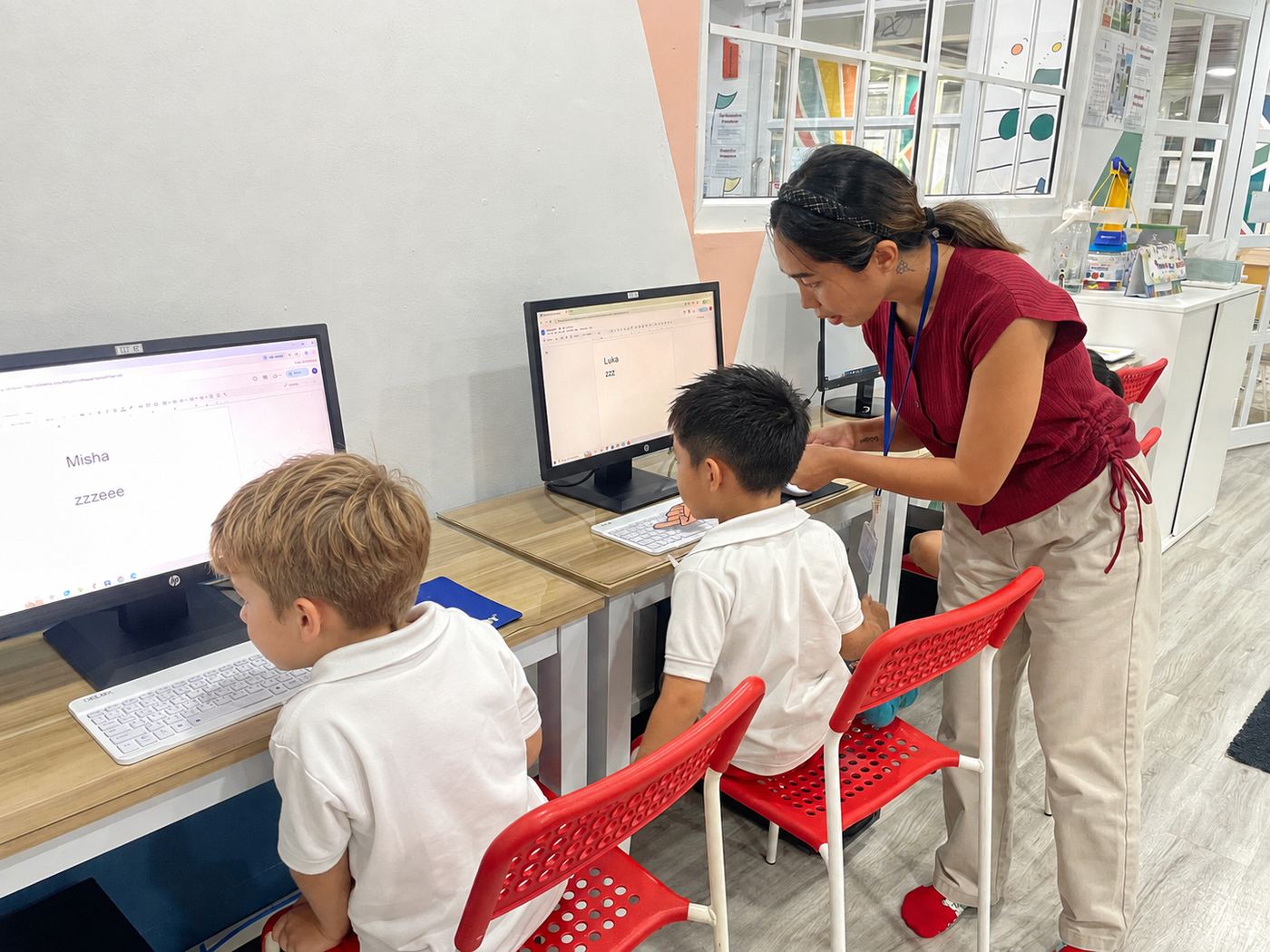 A teacher helping young students with a computer activity