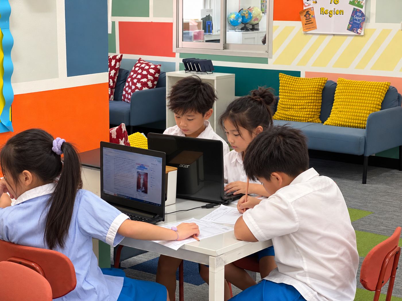 A small group of students collaborating on laptops during independent research
