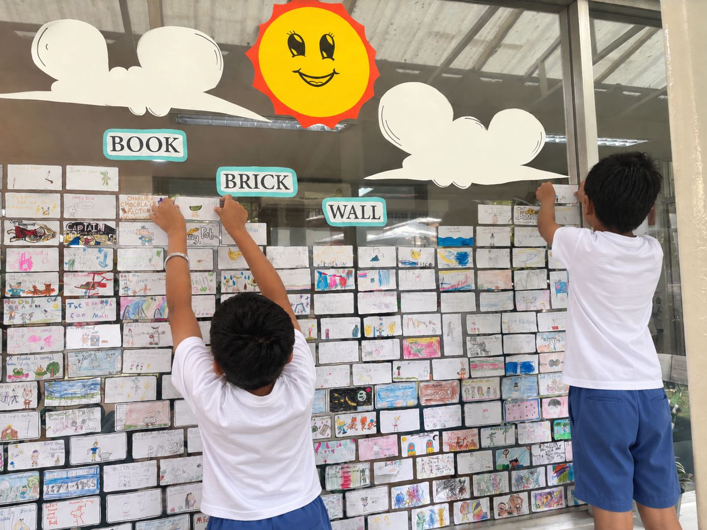 Students adding to a class “Book Brick Wall” reading display
