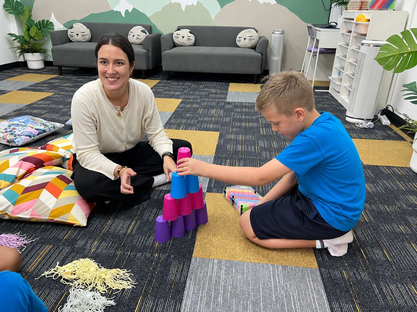 A teacher and student building a tower with sensory stacking cups
