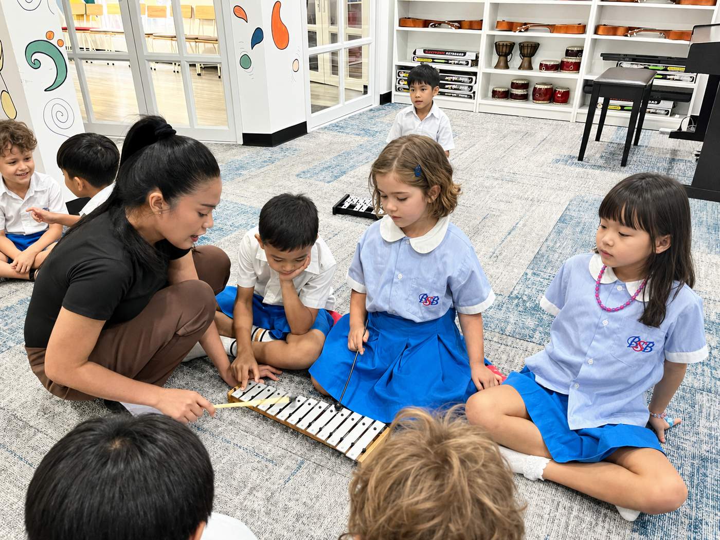 A teacher and small group of students playing a glockenspiel together