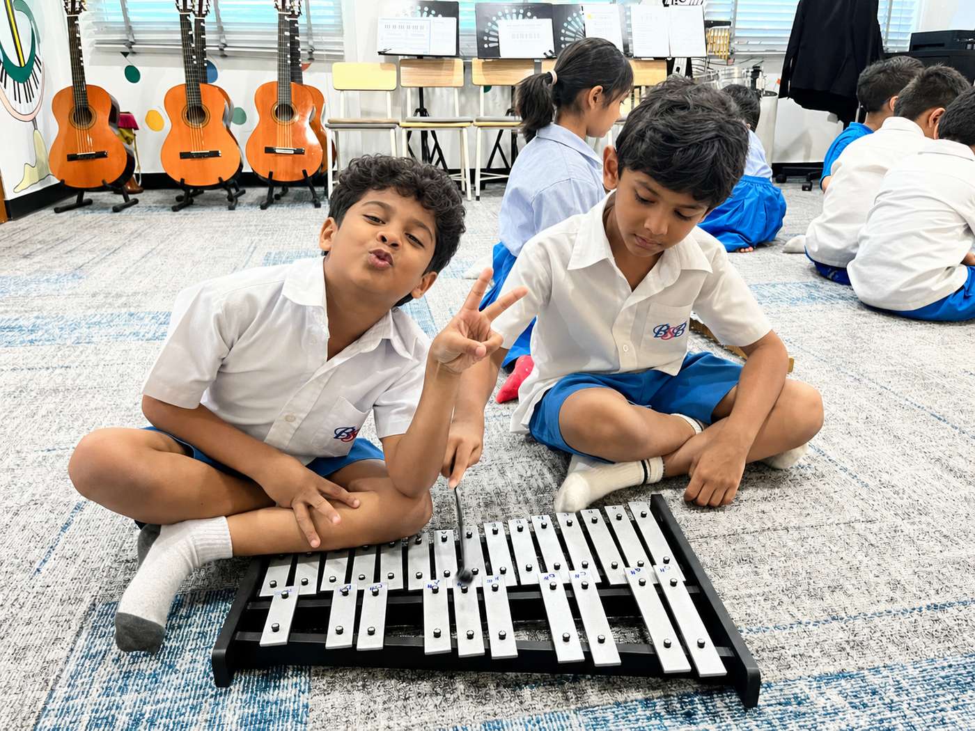 Two students smiling while playing a xylophone together
