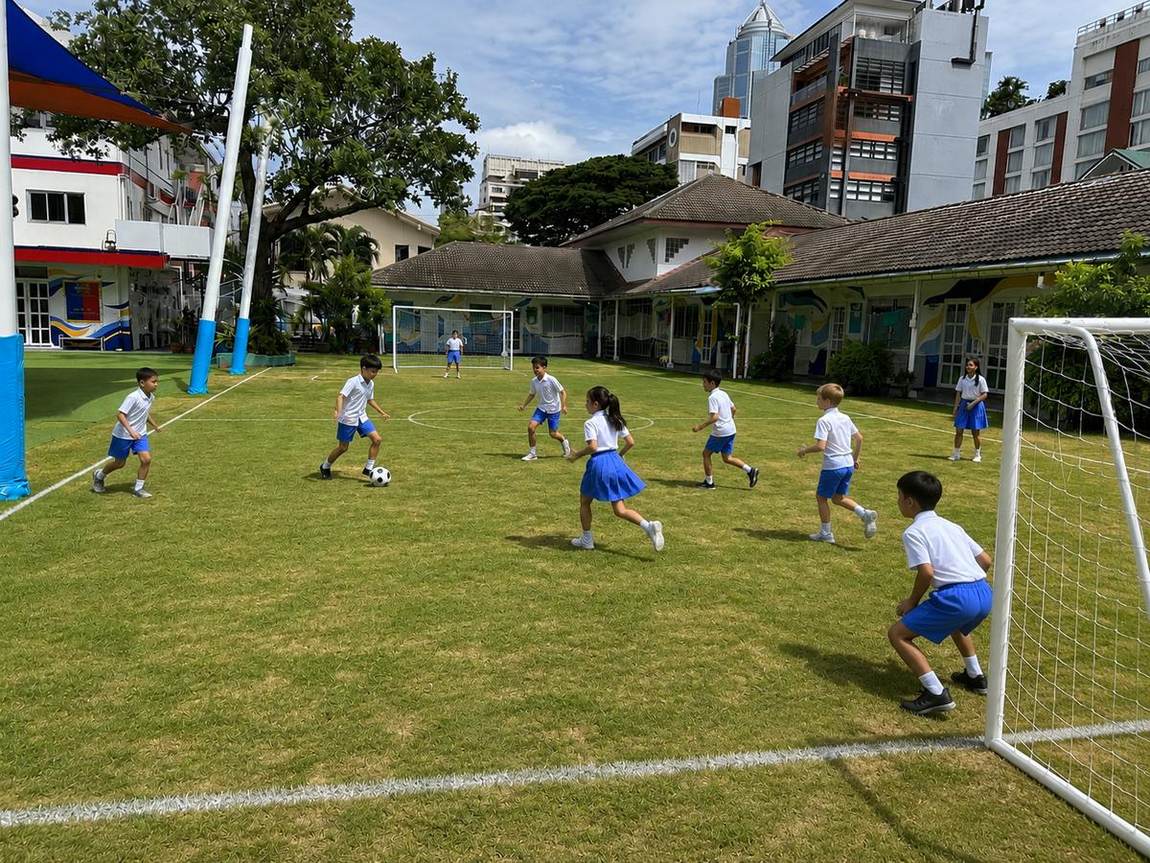 Students playing a ball game with coaches in the gym