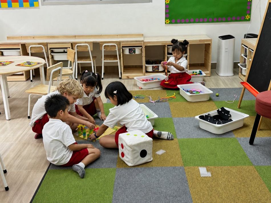 Students playing together with building and lacing toys on the classroom floor