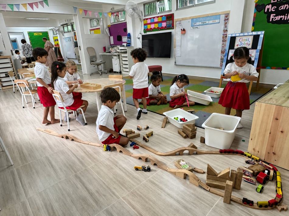 Students sharing a drink while playing with a tricycle outdoors