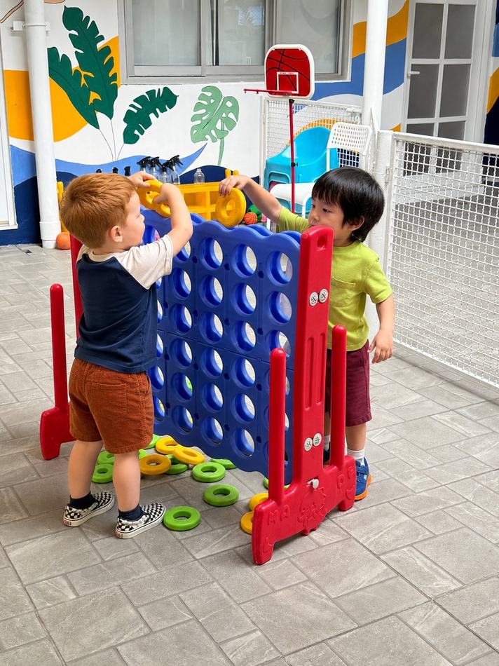 Two students playing a giant connect-four game outdoors