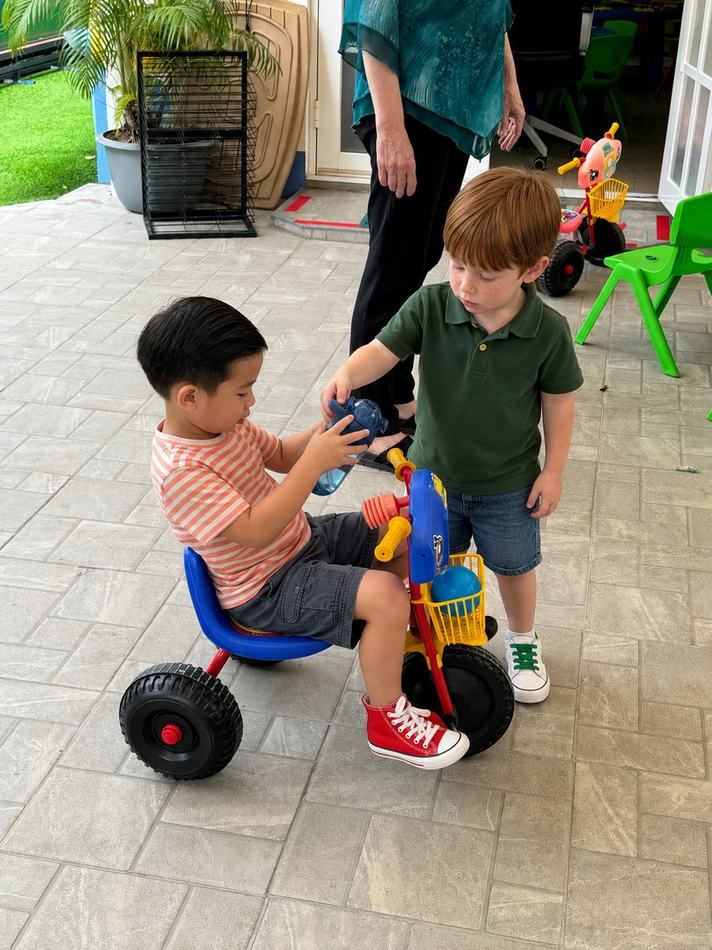 Students playing together with a tricycle outdoors